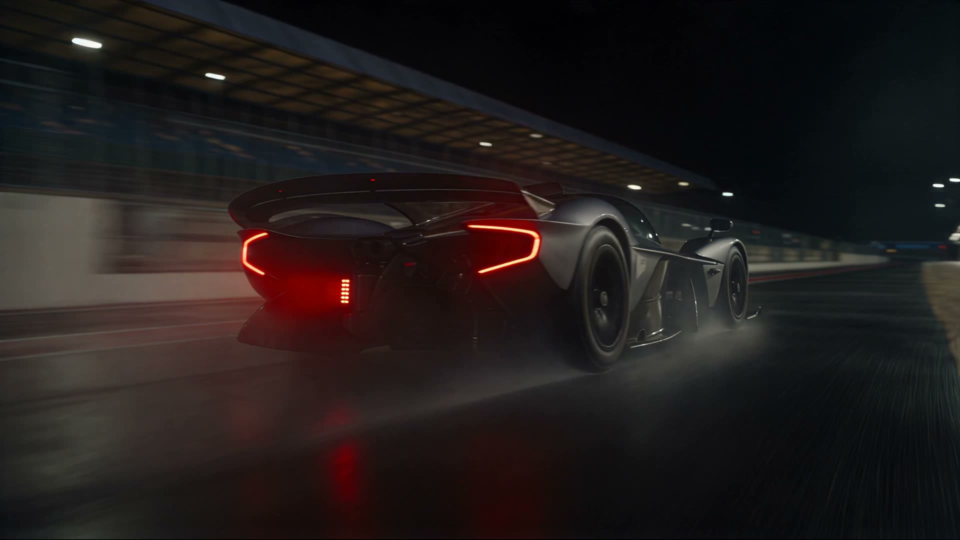 Competition prototype seen from behind as it runs down the pit lane at night, tail lights on the wet surface.